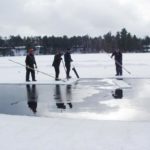 A group of people standing on a frozen pond.