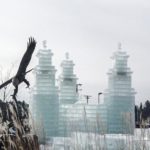 An ice castle with a bird flying over it.