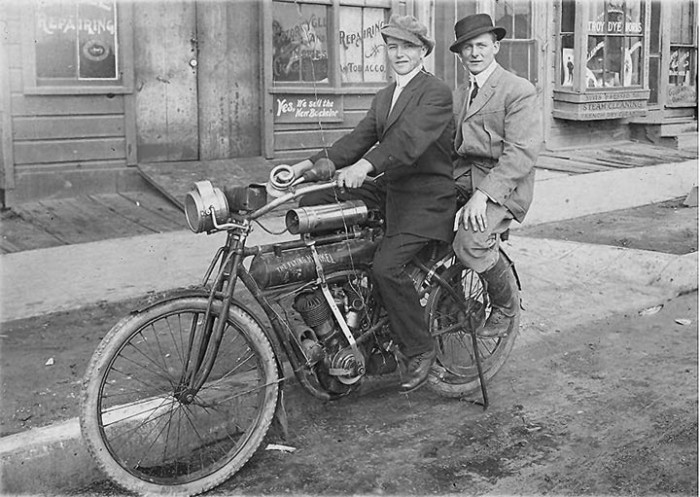 Two men on a motorcycle on the street.