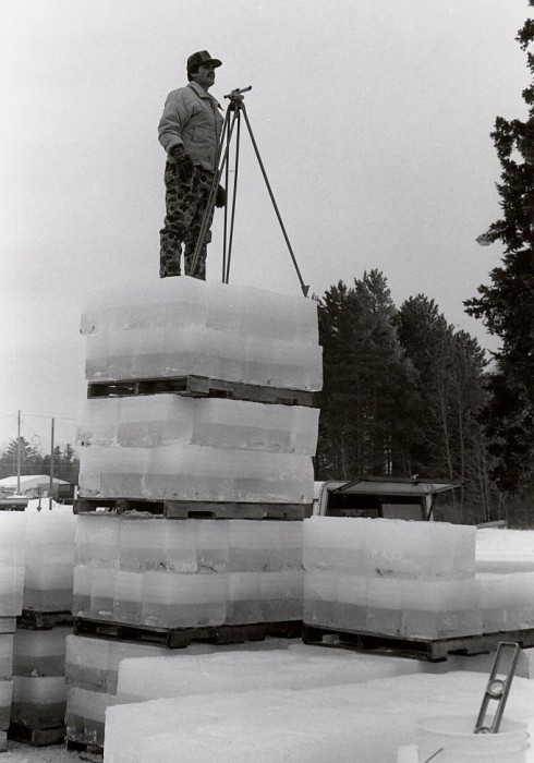 A man standing on a stack of ice blocks.