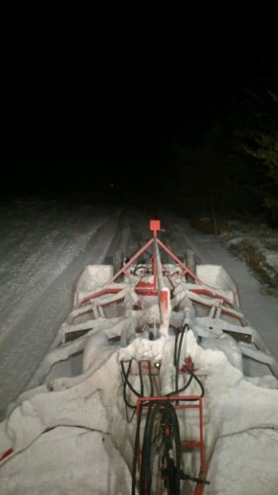 The back of a snowmobile on a snowy road at night.
