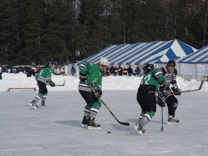 A group of men playing hockey on an ice rink.