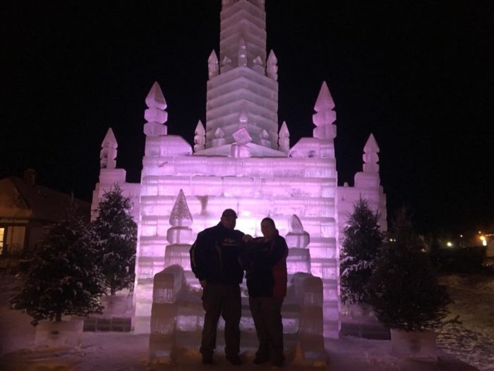 A man and woman standing in front of an ice castle.