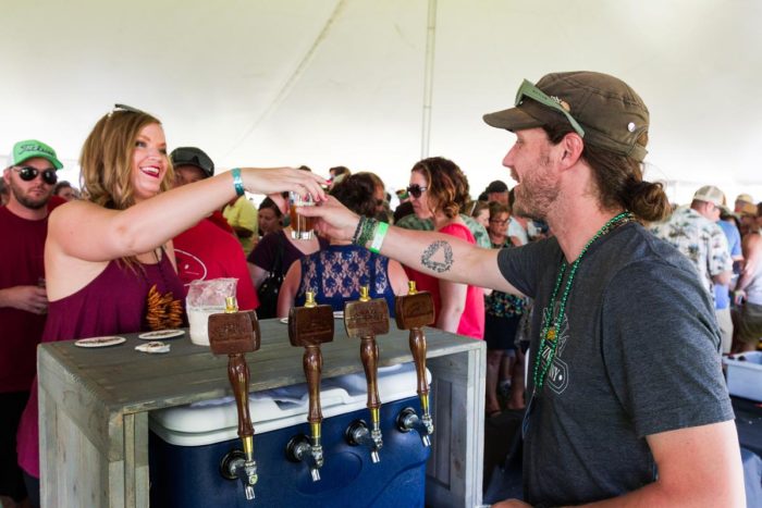 A man is pouring a beer at a tent.