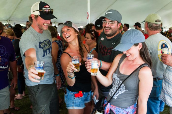 A group of people drinking beer in a tent.
