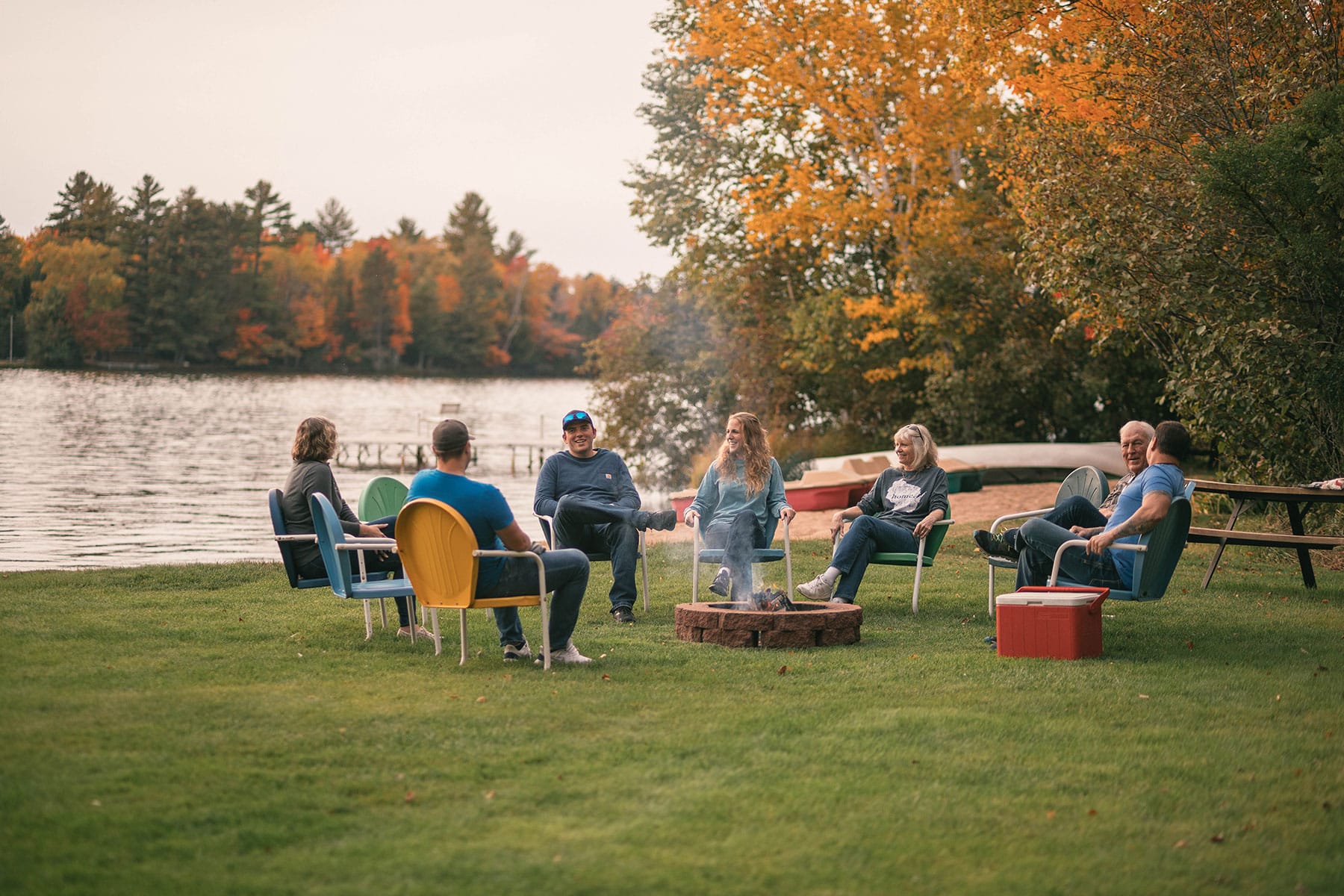 family sitting around a firepit while cmaping in fall