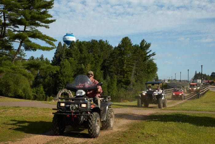 A group of people riding atvs on a dirt road.