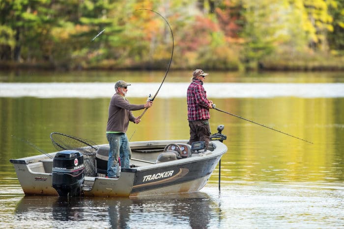 Two men fishing in a small boat on a lake.