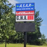 A signboard with advertisements for A.S.A.P. Garage Door Repair, Inc., LiftMaster, and C.H.I. Overhead Doors, set against a backdrop of trees and a clear blue sky showcases their garage door services prominently.