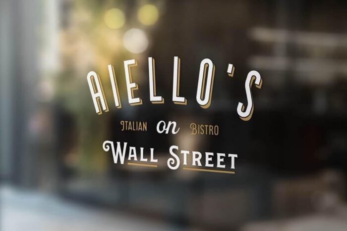 Glass door sign reads: "AIELLO'S Italian Bistro on Wall Street" in white and gold lettering. The background is blurred.