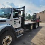 A flatbed truck labeled "Wisconsin Building Supply" is parked next to a forklift at the building supply loading area.