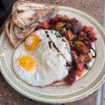 A plate with two sunny-side-up eggs, toast, and a vegetable medley, served on a speckled, round table in our cozy restaurant.