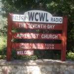 Sign reading "103.5 FM WCWL Radio, The Seventh-Day Adventist Church" with times for Sabbath School at 9:30 AM and Sabbath Worship at 11:00 AM.