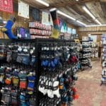 Interior of a store displaying a variety of socks on racks. The shelves are filled with colorful options, and clothing accessories are visible in the background.