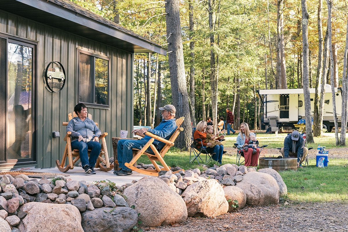 A group of people sitting on the porch of a cabin.