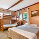 Two bunk beds in a room with wood paneling.