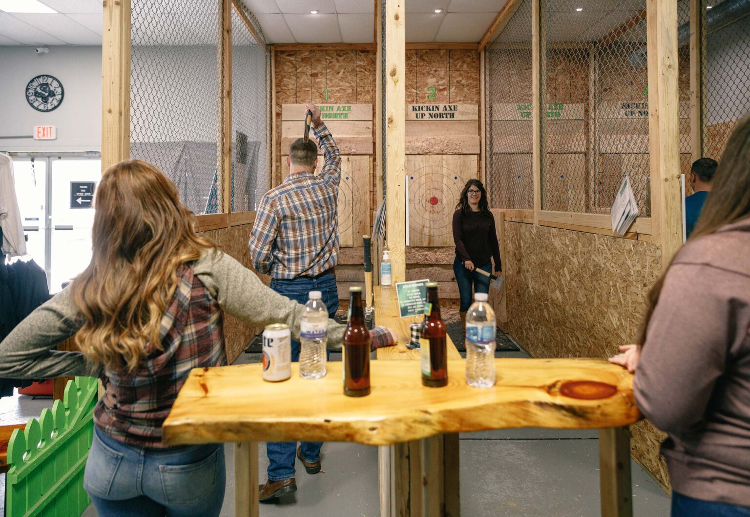 People engaged in axe throwing at an indoor recreational facility.