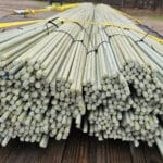 Stacks of bundled fiber optic cables on a wooden surface with equipment in the background.