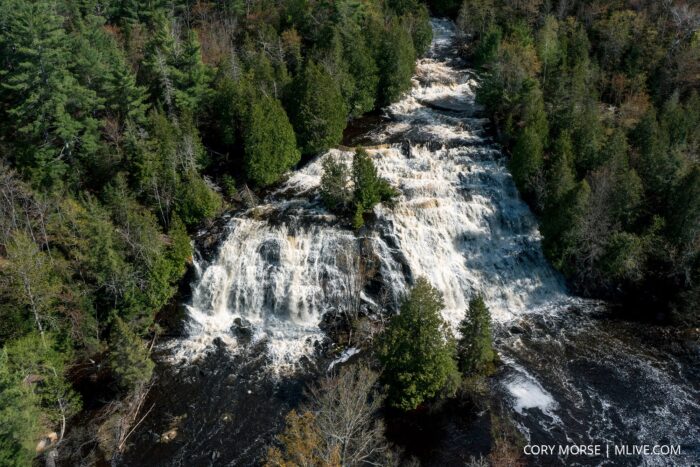 Aerial view of Laughing Whitefish Falls in Michigan, showcasing waterfalls cascading over rocks surrounded by dense trees. Photo credit: Cory Morse / MLive.com.