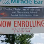 Old Paths Christian Ministries and Elementary School sign with a banner below reading 'Now Enrolling 4K & 5K Students' and a contact number.