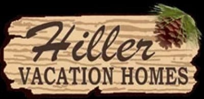 Sign reads "Hiller Vacation Homes" with a wood texture and a pinecone in the corner.