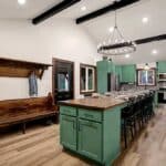 Kitchen and dining area featuring green cabinetry, a wooden island with bar stools, bench seating, and a chandelier.