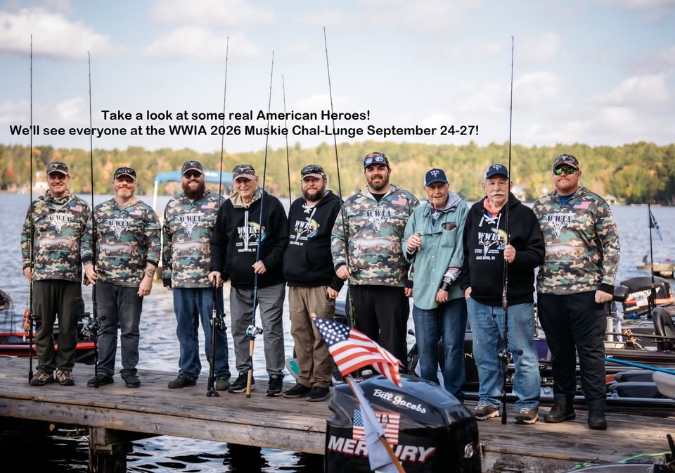 Nine people in camouflage hoodies pose with fishing rods on a dock by a lake, with boats and trees in the background. A sign announces the WWIA 2026 Muskie Challenge event.