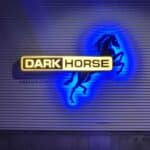 A sign reading "DARK HORSE" is illuminated in yellow, with a black horse silhouette and blue lighting on a corrugated wall.
