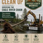 Excavator on a barge removes tree debris from a lakeshore. Inland Lakes Dredge & Dock Works logo and contact information shown.