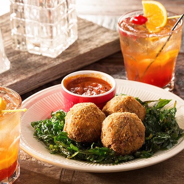 A plate of meatballs and a drink on a table.