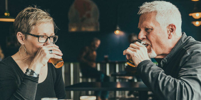 A man and woman drinking beer at a bar.