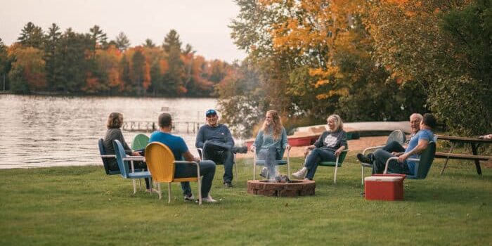 family sitting around a firepit while cmaping in fall