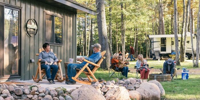 A group of people sitting on the porch of a cabin.