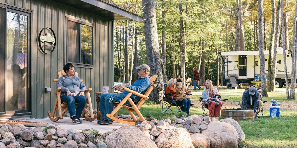 A group of people sitting on the porch of a cabin.