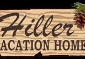 Sign reads "Hiller Vacation Homes" with a wood texture and a pinecone in the corner.
