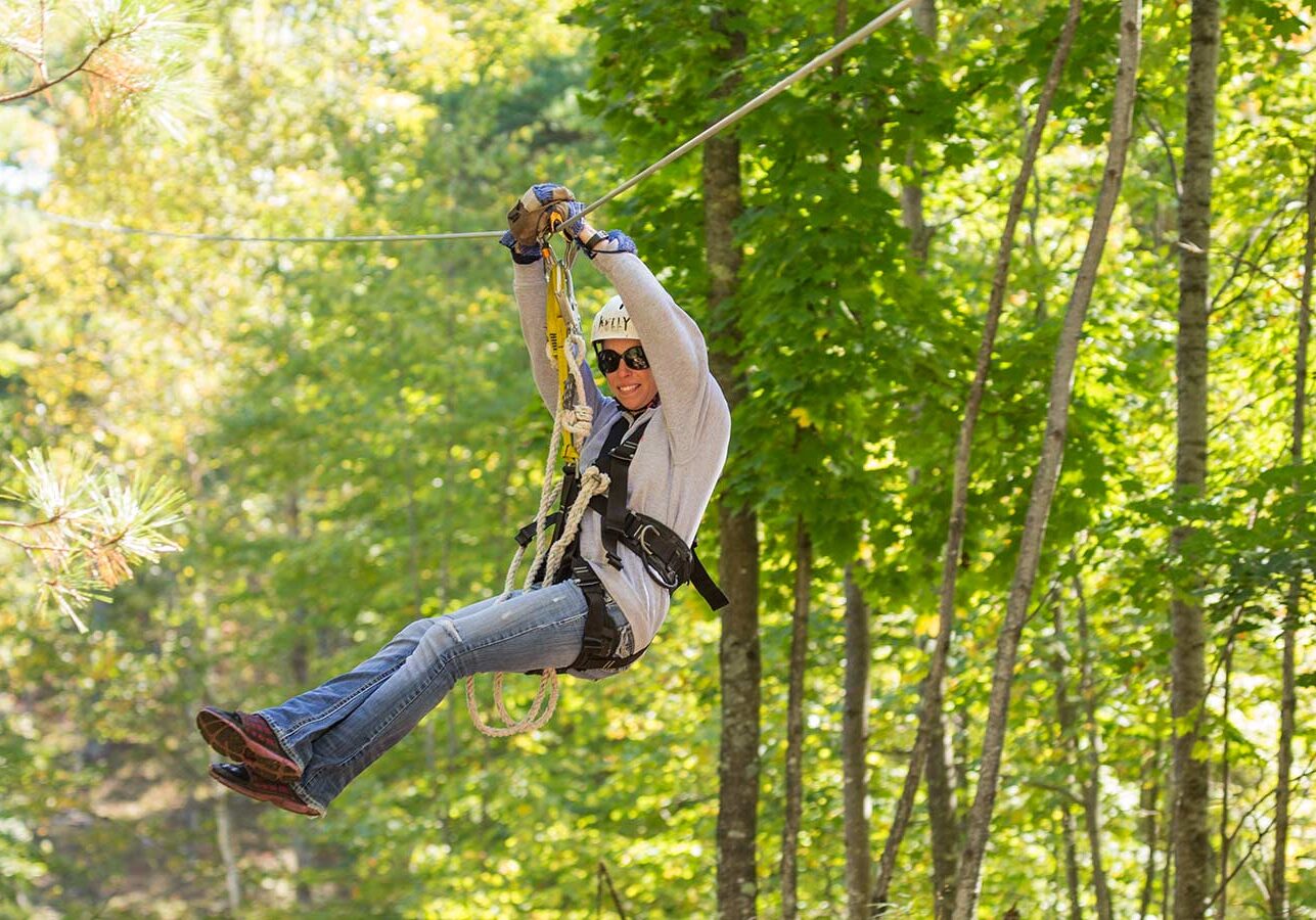A man on a zip line in the woods.