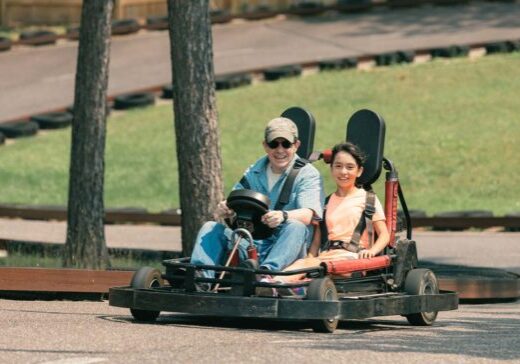 Two people riding go - karts down a road.