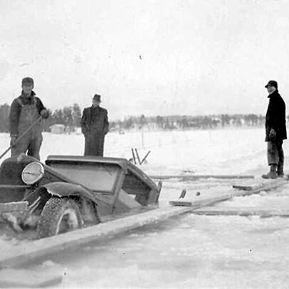 A group of men standing next to a car in the snow.